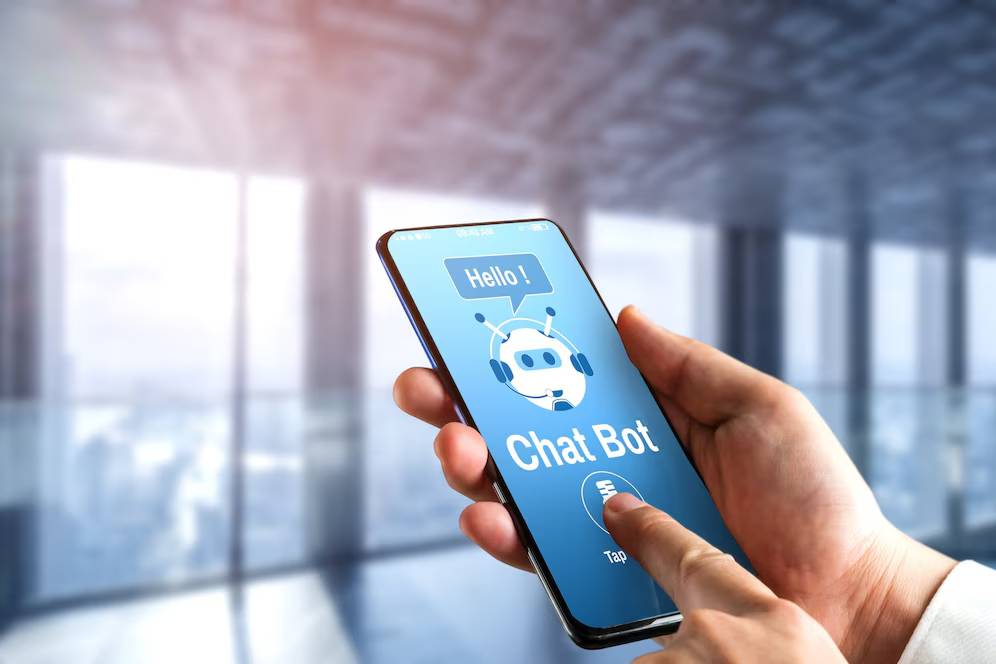 Person holding a smartphone displaying a chatbot interface, in a modern office setting.