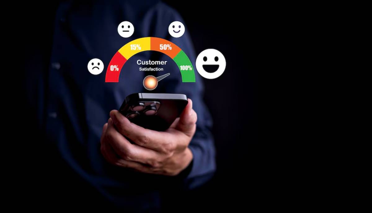Businessman using smartphone with digital customer satisfaction meter and emoticons floating above it.