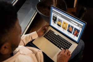 Man shopping on a fashion store website on his laptop in a dark room.