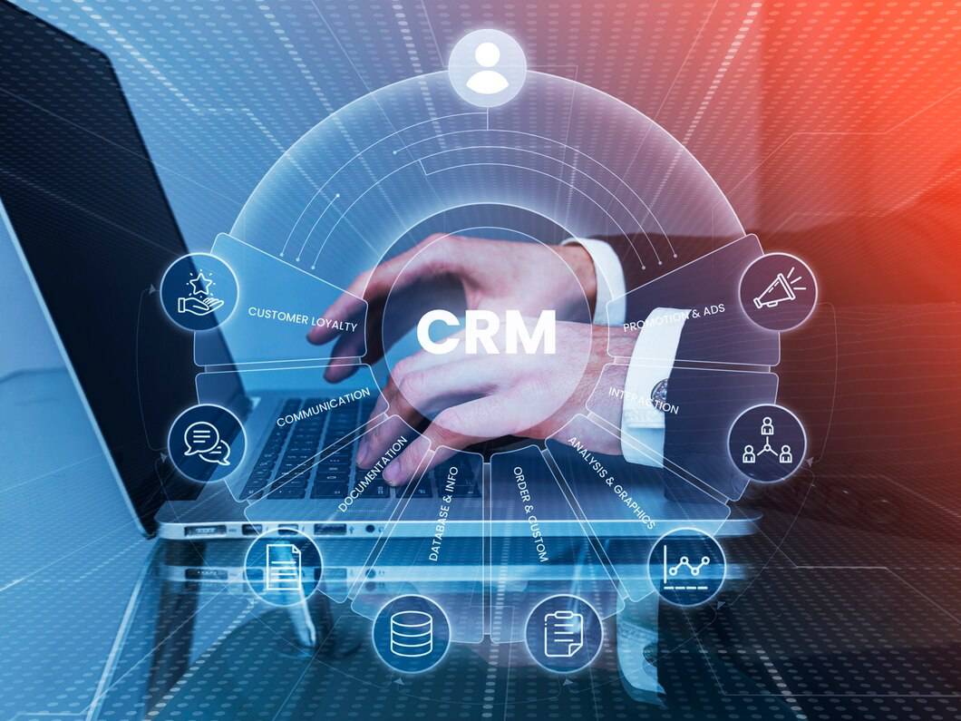 Person interacting with a futuristic CRM interface on a laptop, showing various business management icons and data analytics.