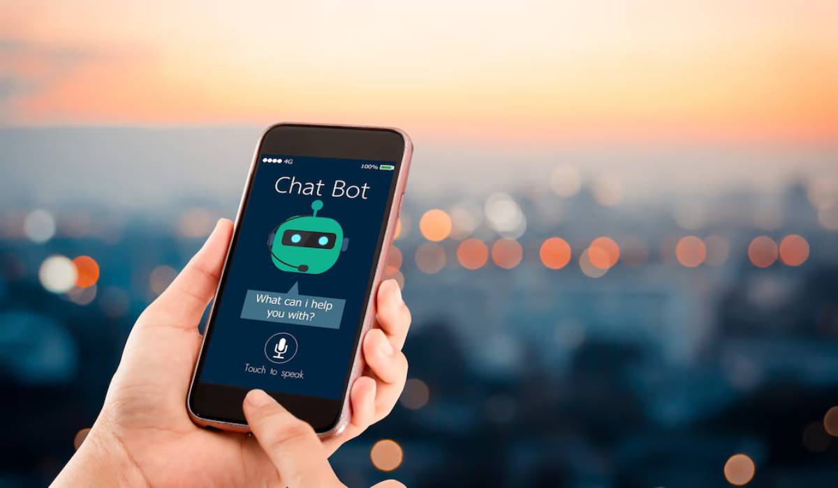 Hand holding smartphone displaying Chat Bot app with sunset cityscape in background.
