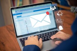 Person checking emails on a laptop with icons indicating notifications and social interactions.