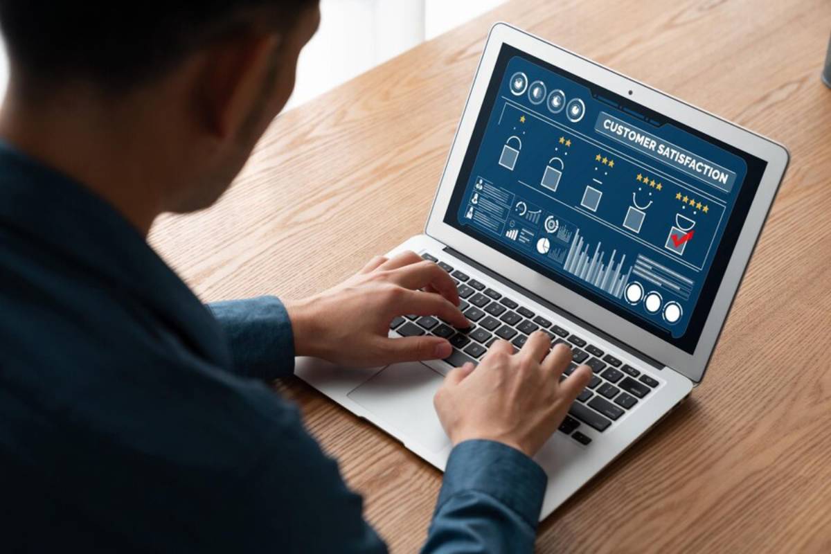 Man analyzing customer satisfaction metrics on a laptop screen at a wooden table.