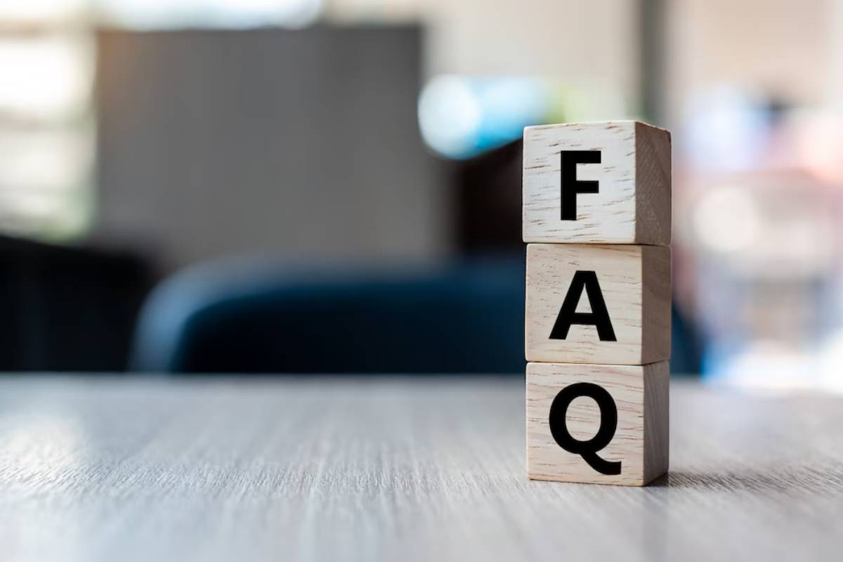 Three wooden blocks stacked on a table spelling out FAQ in a softly blurred office background.