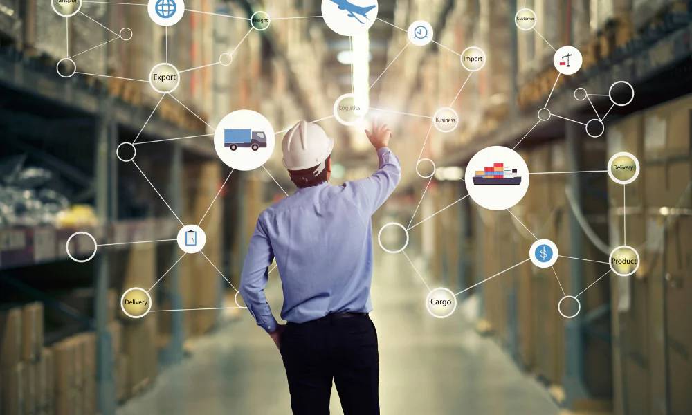 Man in hard hat pointing at logistics network icons overlaying a warehouse scene.